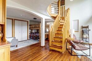A spacious room with a wooden staircase, a bed with a colorful blanket, and a chair. - Deck & Views! Family Retreat Near Rmnp (Grand Lake)