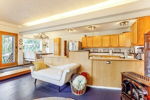 A modern kitchen with wooden cabinets, a built-in refrigerator, and a dining area with a white sofa and a basket of items.
