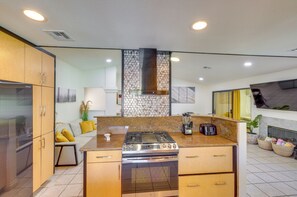 A modern kitchen with a central island, stainless steel appliances, and a tiled backsplash.