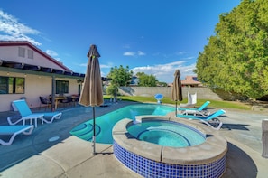 A backyard with a swimming pool, lounge chairs, and a dining area.
