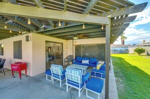 An outdoor patio with a covered seating area, a red Coca-Cola cooler, and a glass table.