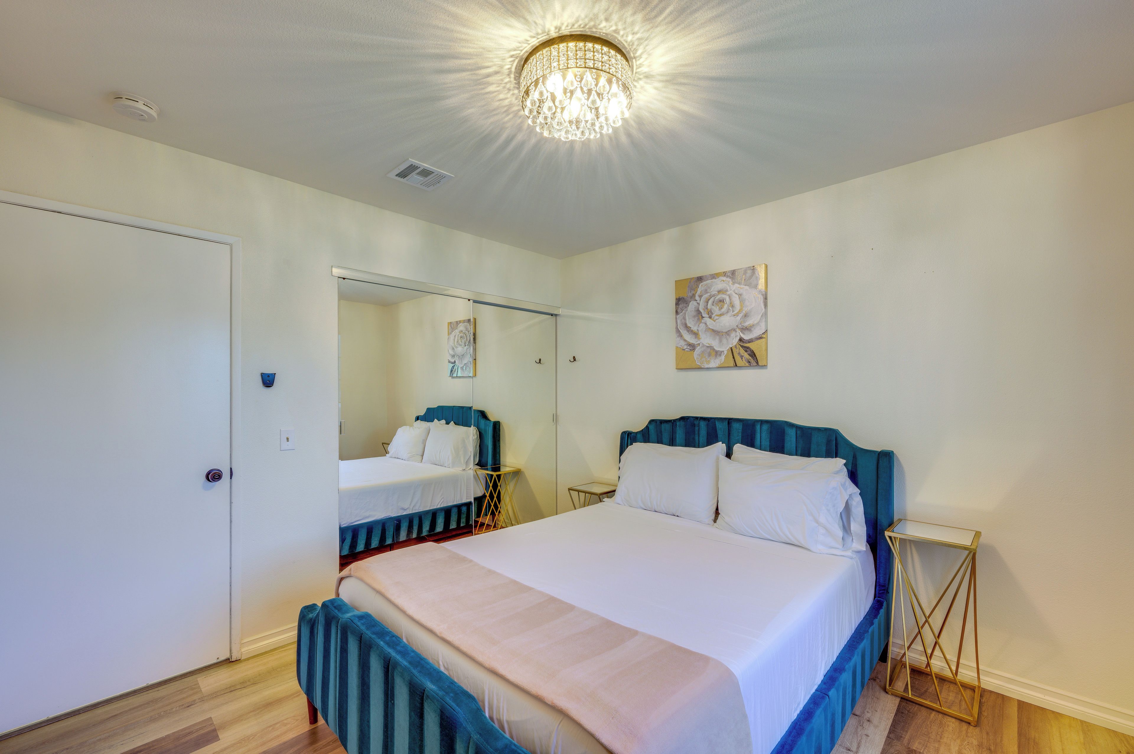 Quarto de hotel com cama, mesa de cabeceira, espelho e um quadro na parede.