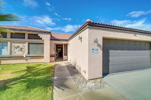 A residential building with a garage, a covered entryway, and a landscaped front yard.