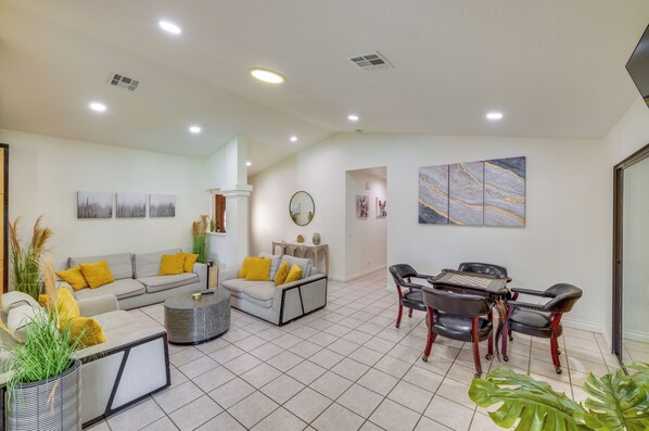 A living room with a sofa, coffee table, and a dining area with chairs and a table.