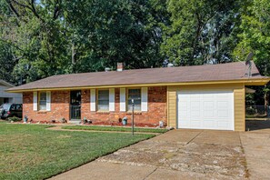 A single-story brick house with a garage, a front porch, and a satellite dish.