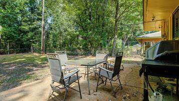 An outdoor patio with a table and chairs, surrounded by trees.