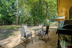 An outdoor patio with a table and chairs, surrounded by trees. - 4 Mi to Graceland! Cozy Home w/ Patio & Yard (Memphis)