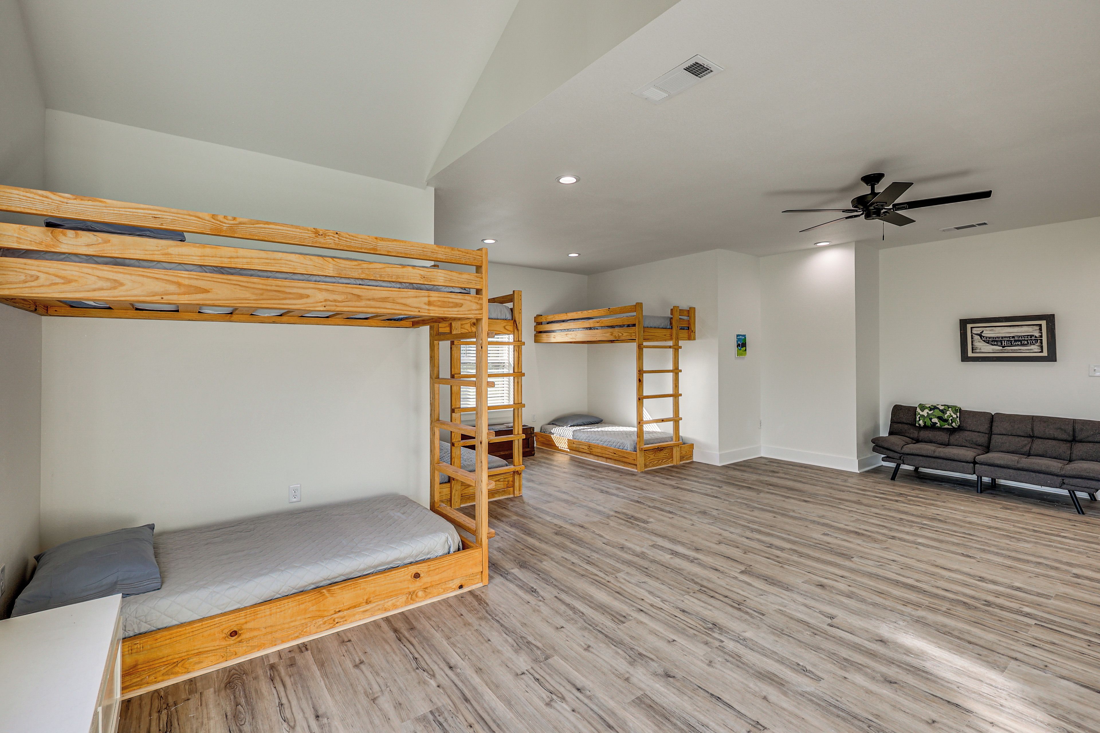 A room with bunk beds, a sofa, and a ceiling fan.