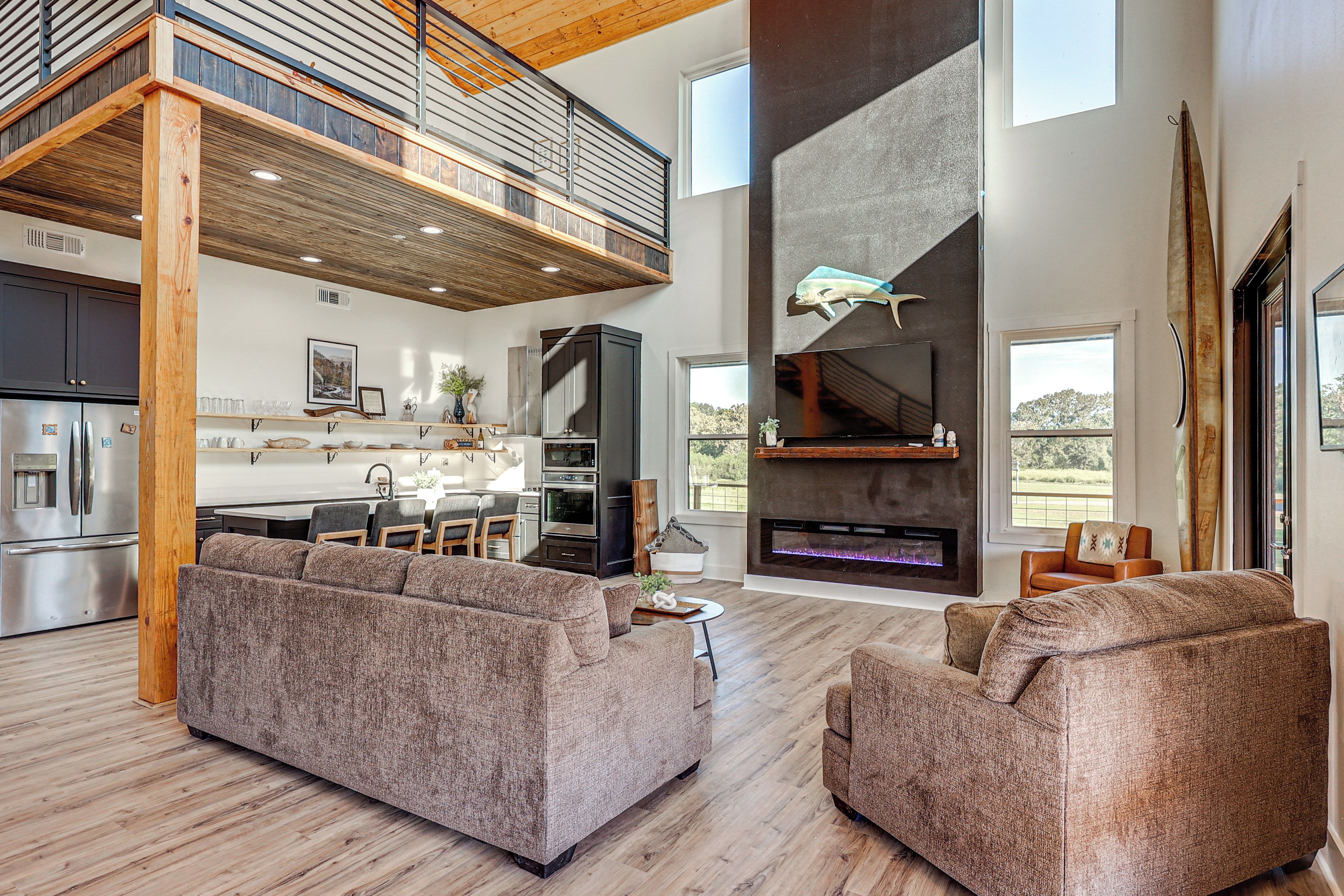 A spacious living area with a high ceiling, a built-in fireplace, and a kitchen with modern appliances.