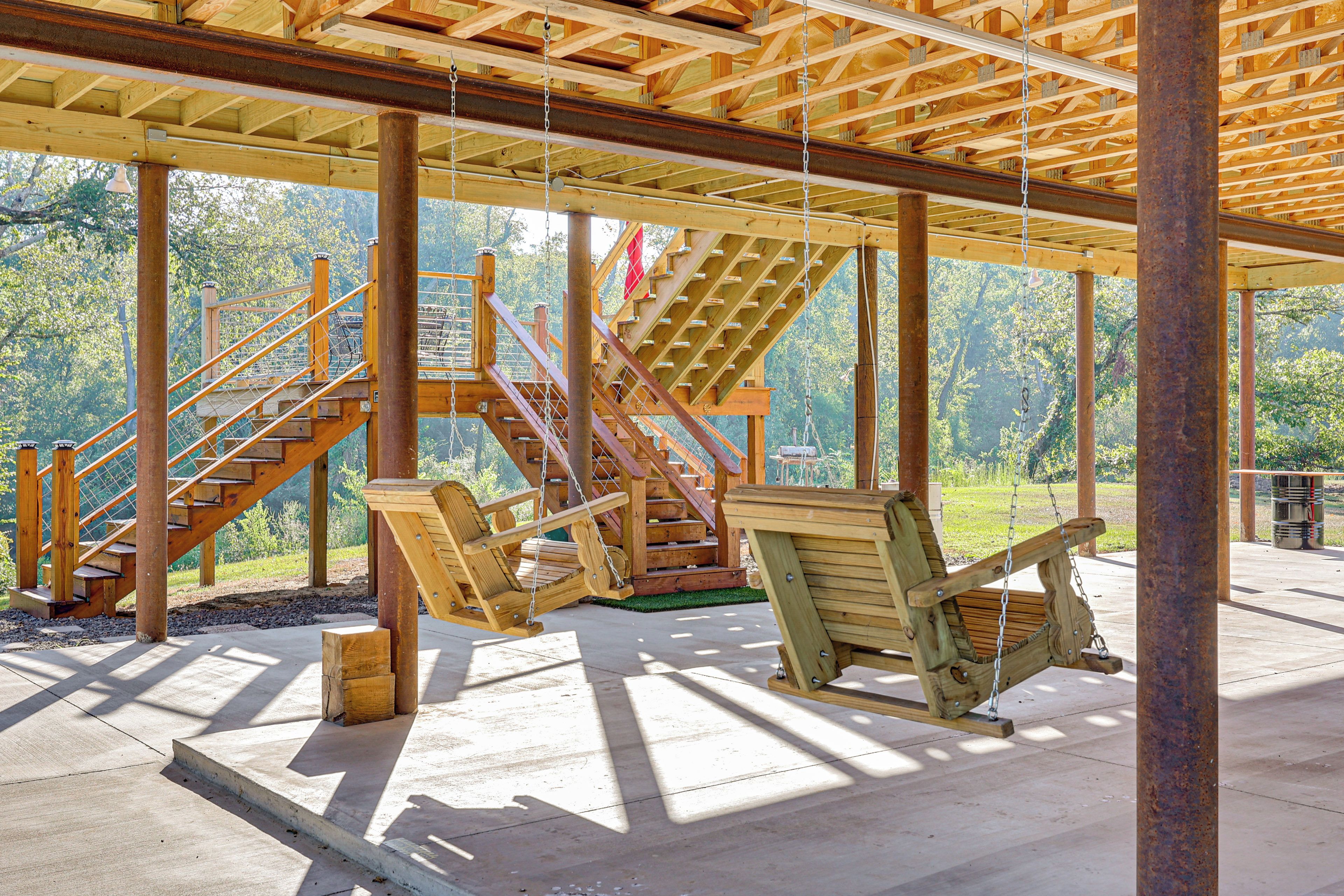 A wooden deck with a swing set and a staircase leading to a higher level.