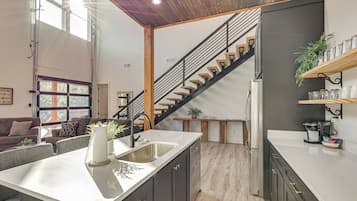 A modern kitchen with a central island, a built-in sink, and a staircase leading to an upper level.