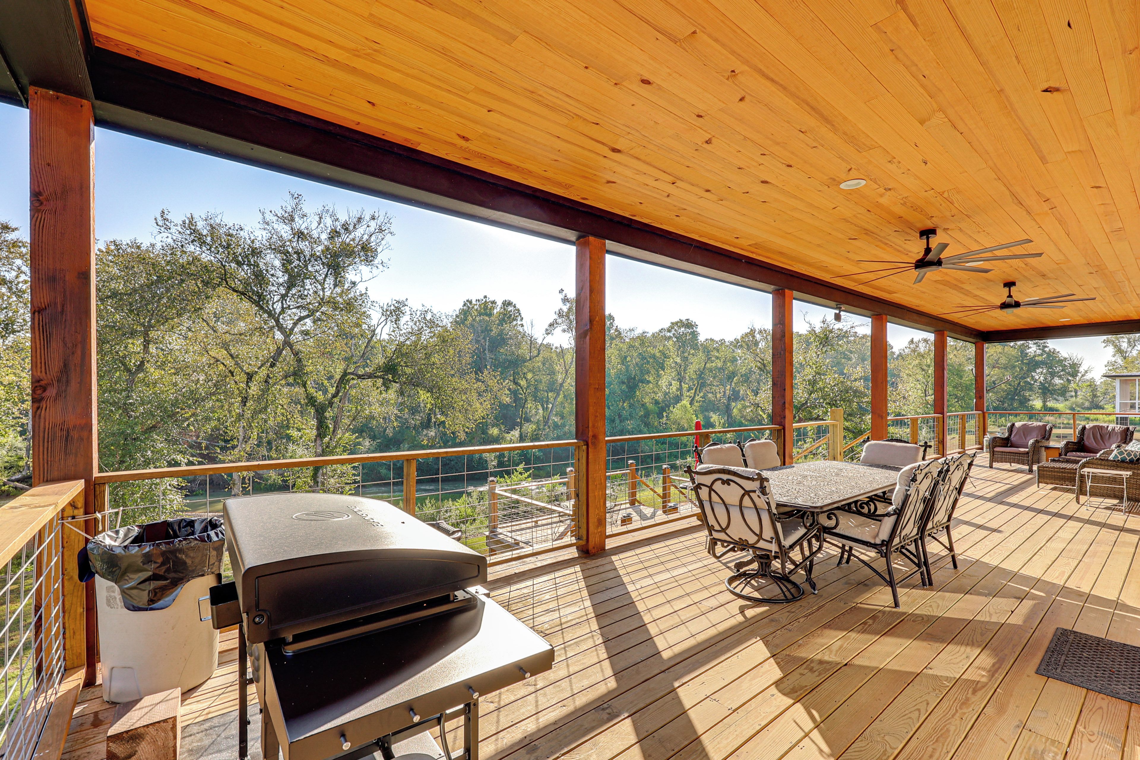Una terraza exterior con una parrilla, zona de estar y vista al río.