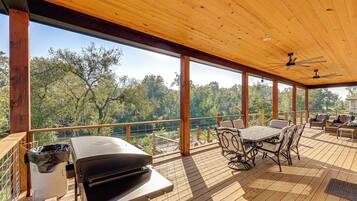 Una terraza exterior con una parrilla, zona de estar y vista al río.
