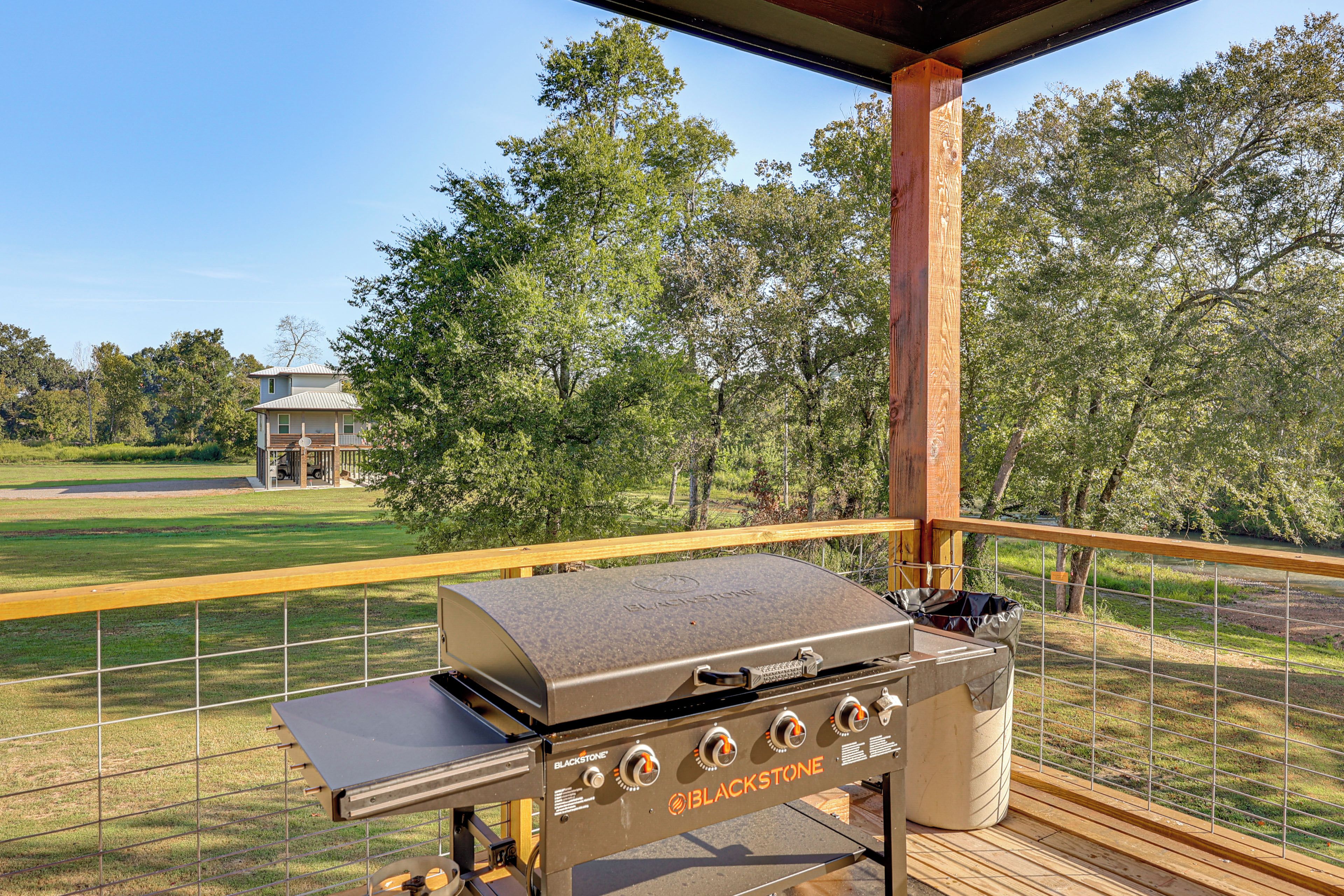 An outdoor grill area with a view of a golf course and a house in the background.