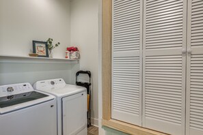 A laundry area with two washing machines, a shelf with a framed picture, and a closed closet with louvered doors. - 'river Bank' Spacious Waterfront Group Getaway (Nashville)