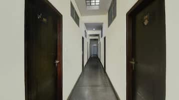 Un couloir étroit, avec des portes de part et d’autre, qui mène à une pièce dont une fenêtre se trouve au fond.