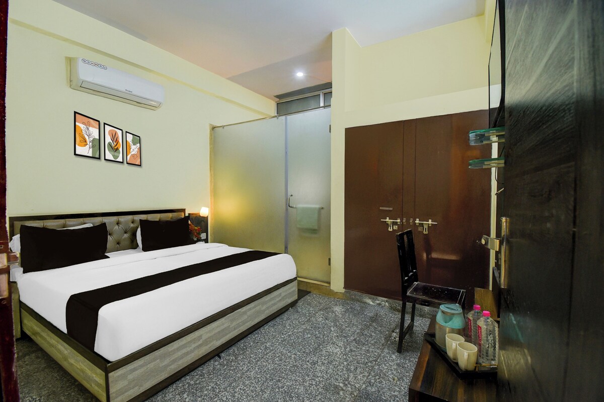 A hotel room with a bed, a wardrobe, a mirror, and a small table with toiletries.