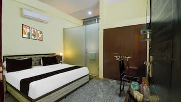 Une chambre d’hôtel comprenant un lit, une armoire, un miroir et une petite table avec des articles de toilette.