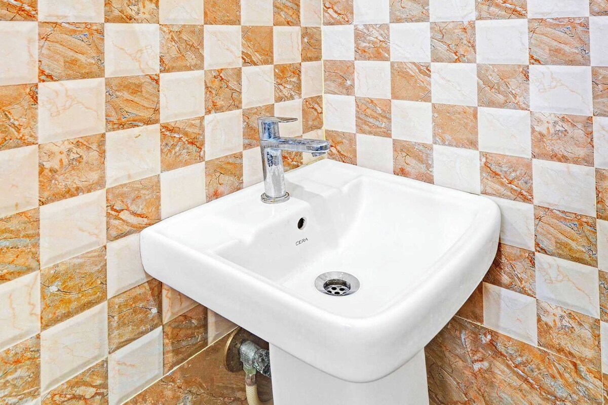 A bathroom with a white sink, checkered tile backsplash, and a mirror above it.