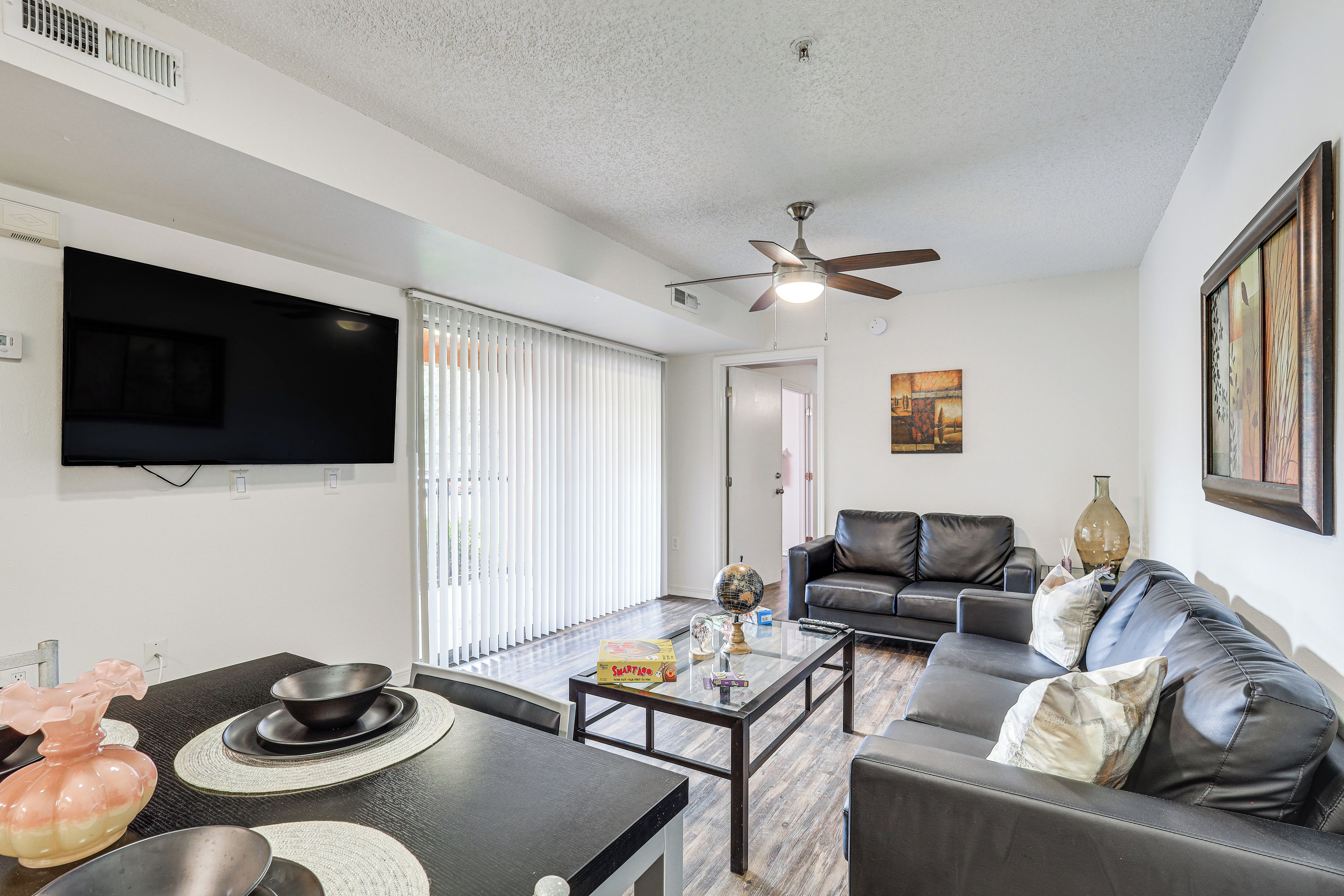 A modern living room with a flat-screen TV, a ceiling fan, a sofa, and a coffee table.