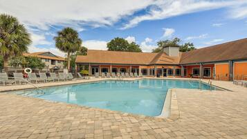 A swimming pool with lounge chairs and a brick patio.