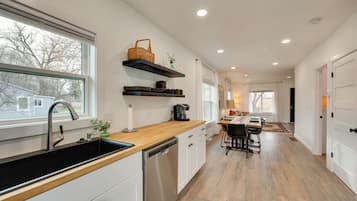 A modern kitchen with a large window, built-in dishwasher, and wooden countertop.