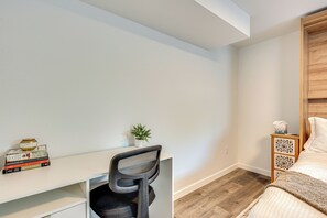 A bedroom with a wooden headboard, a white desk with a chair, a small plant, and a bedside table with a tissue box. - Spacious Duplex Duo: 14 Mi to Pearl Street Mall (Erie)