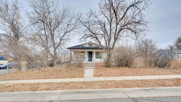 A small, single-story house with a front porch and a fenced yard.