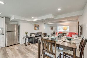 A modern kitchen with a stainless steel refrigerator, a dining area with a wooden table and chairs, a gray sofa, and a red couch. - Spacious Duplex Duo: 14 Mi to Pearl Street Mall (Erie)