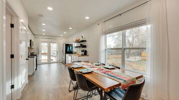 A modern kitchen with white cabinets, a wooden countertop, and a large window.