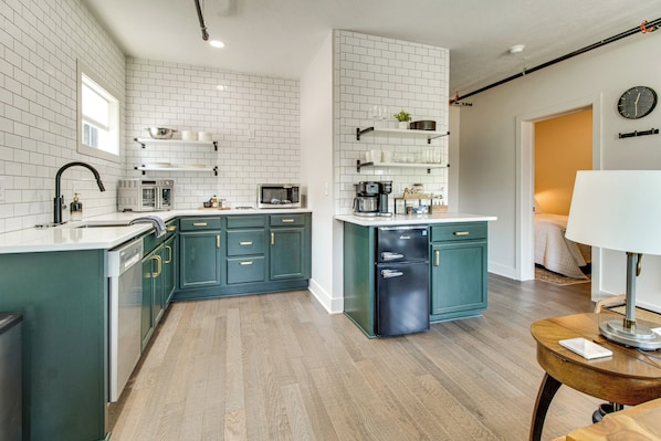 Una cocina moderna con azulejos blancos tipo metro, un microondas integrado y un refrigerador negro.