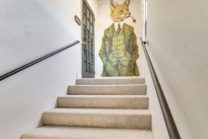 Una escalera con una escultura de un zorro con traje fijada a la pared.