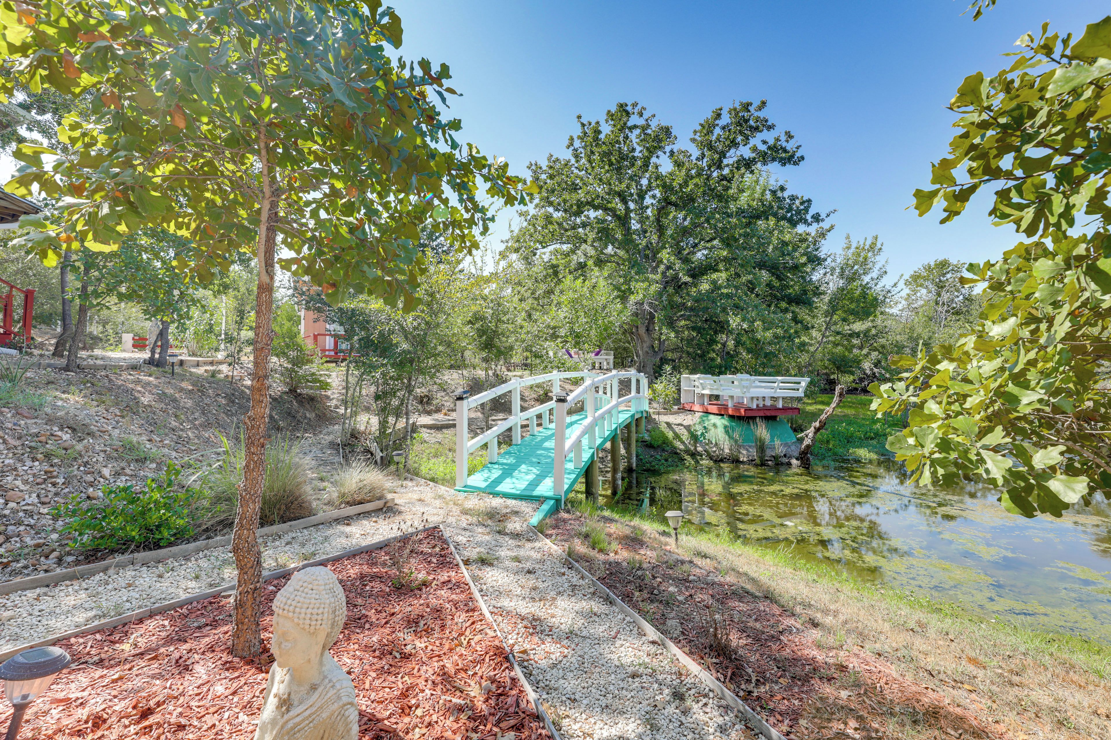 A serene park with a wooden bridge, a pond, and a statue.