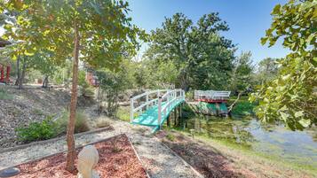A serene park with a wooden bridge, a pond, and a statue.