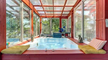 A sunroom with a glass ceiling, a small pool, and seating areas.