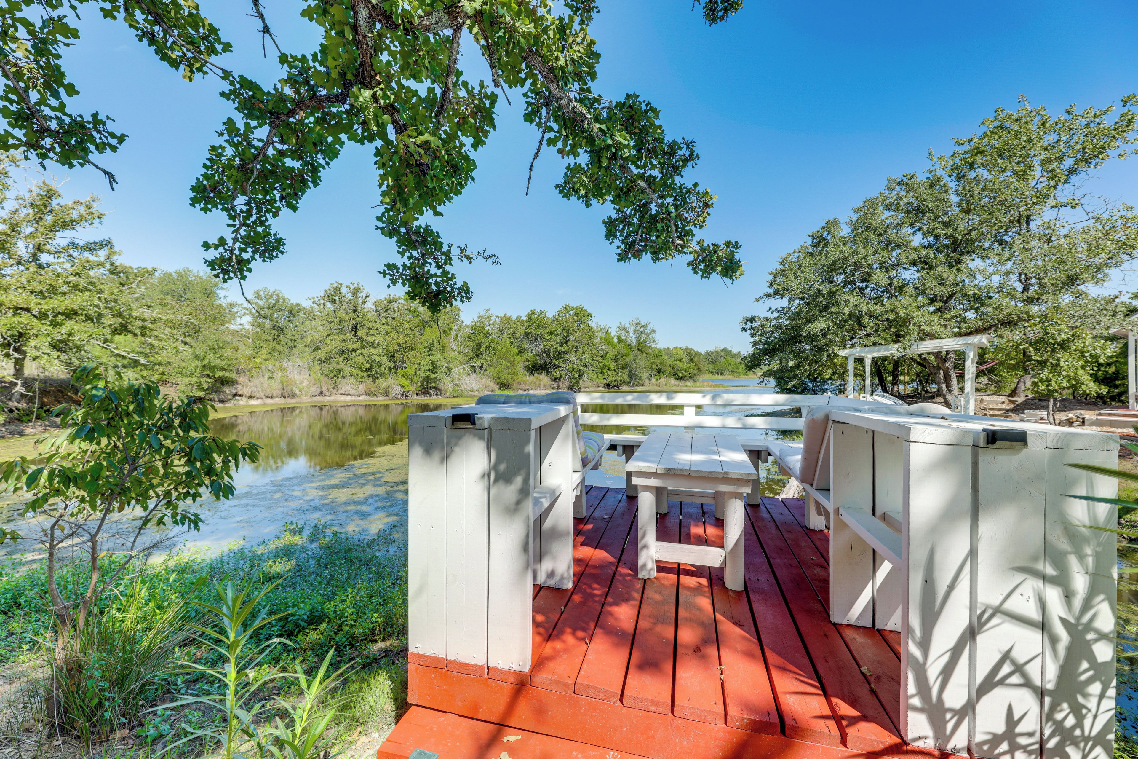 A wooden deck with a table and benches overlooking a body of water.