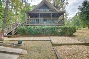 A wooden cabin with a porch, surrounded by trees and a gravel path. - Deep-water Lake Sinclair Escape in Quiet Cove (Milledgeville)