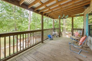 A wooden deck with a covered area, outdoor furniture, and a view of a wooded area. - Deep-water Lake Sinclair Escape in Quiet Cove (Milledgeville)