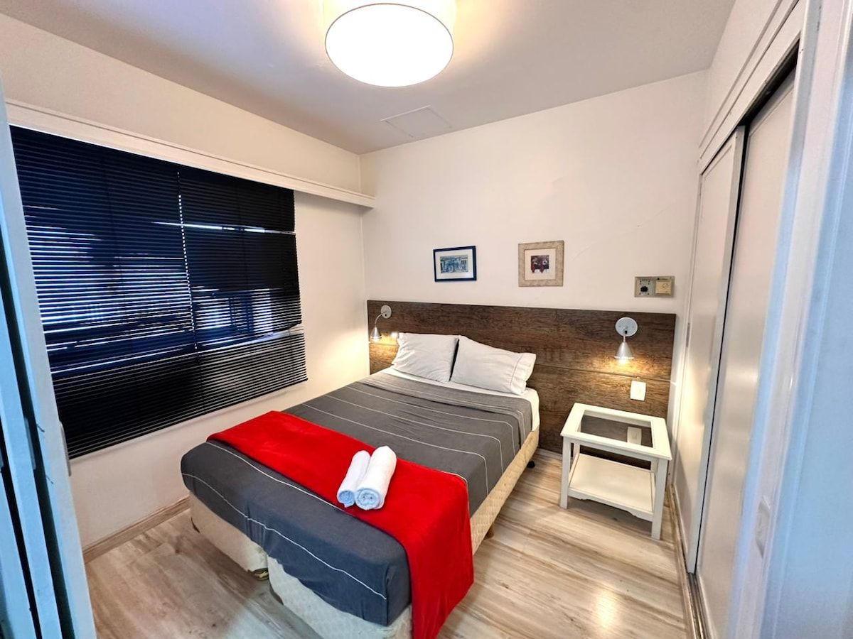 Una camera da letto con un letto, un comodino e una finestra con persiane.