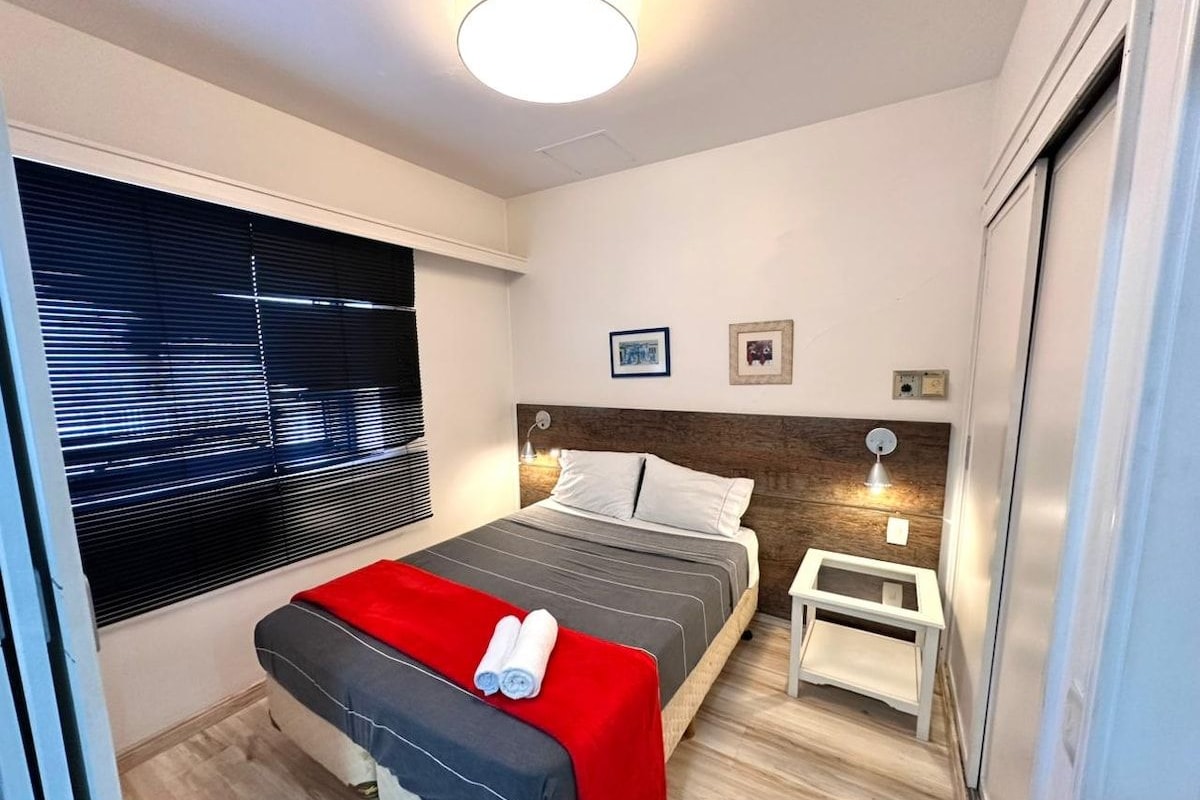 Ein Schlafzimmer mit einem Bett, einem Nachttisch und einem Fenster mit Jalousien.