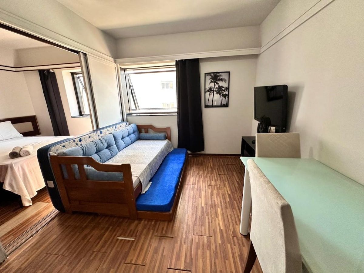 Ein Zimmer mit einem Bett, einem Schreibtisch, einem Stuhl, einem Fernseher und einem Fenster.