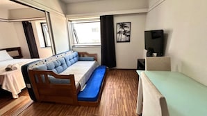 A room with a bed, a desk, a chair, a TV, and a window. - Le Premier Suites (São Paulo)
