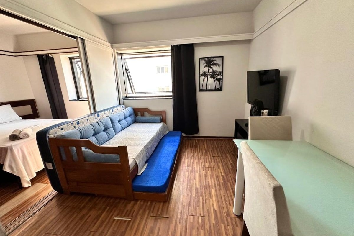Ein Zimmer mit einem Bett, einem Schreibtisch, einem Stuhl, einem Fernseher und einem Fenster.