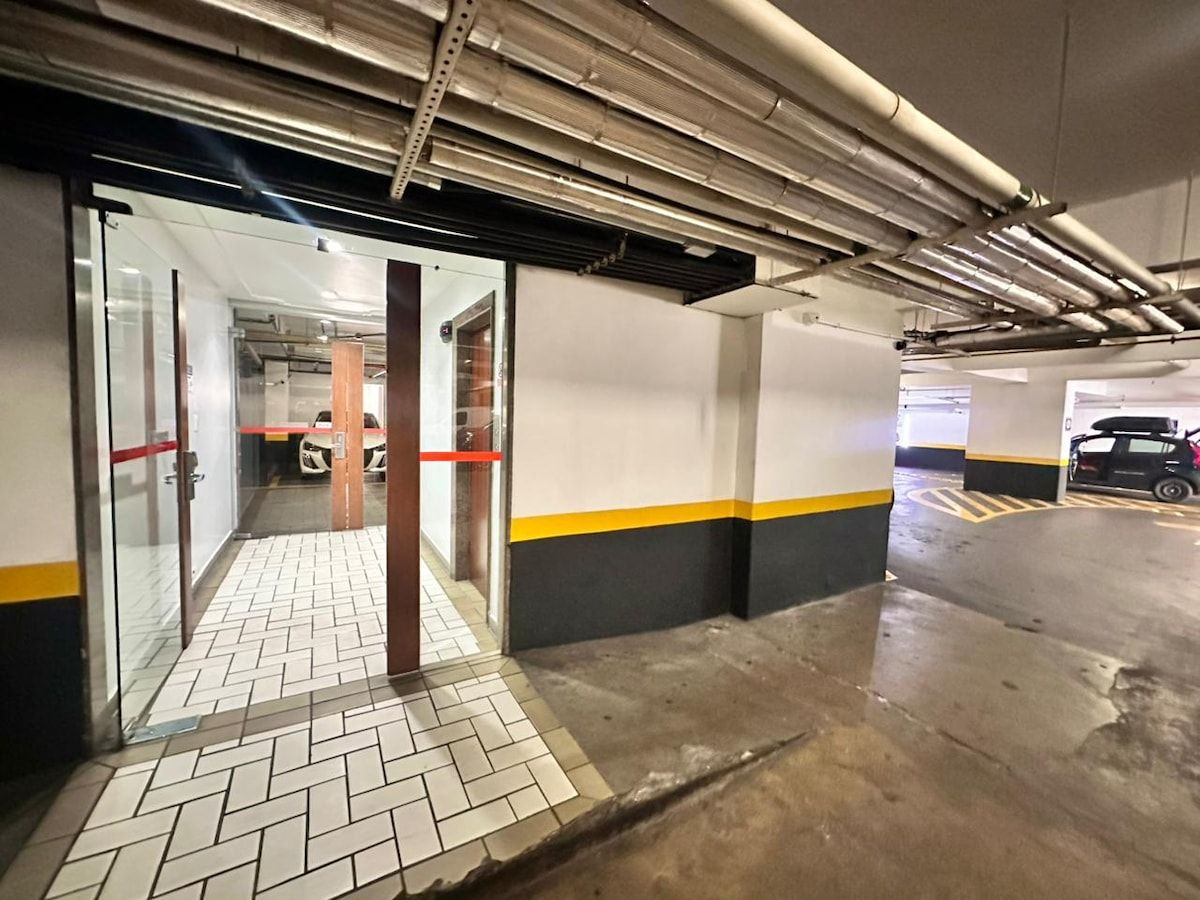 Un estacionamiento interior con suelo de baldosas, paredes de hormigón y vigas estructurales visibles.