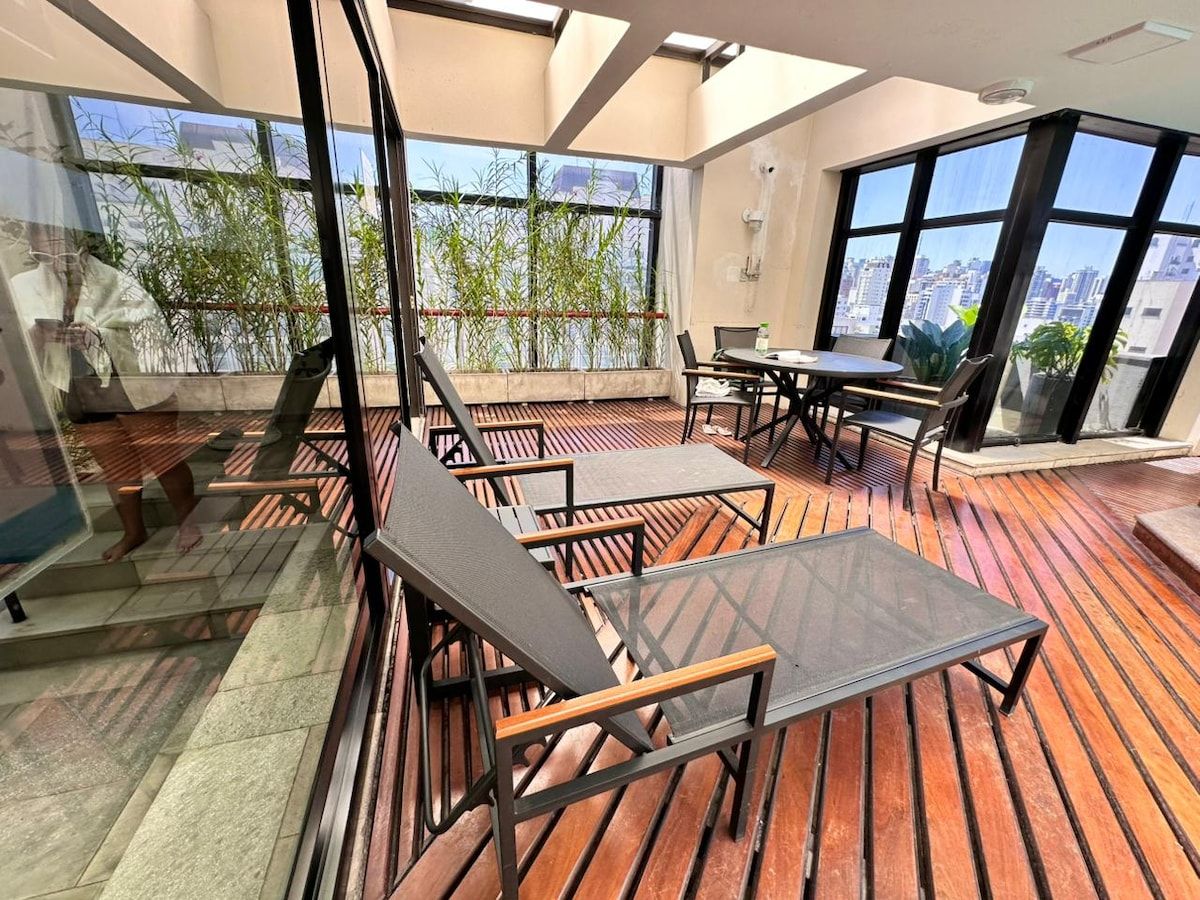 Un'area relax esterna moderna con tavoli e sedie, ampie finestre e vista sulla città.
