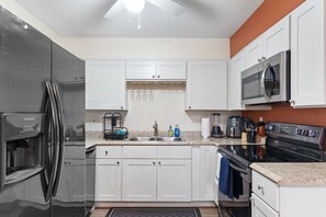A modern kitchen with white cabinets, stainless steel appliances, and a granite countertop. - Remote Ready 1BR - Pet Friendly 5 Min to Ybor (Tampa)