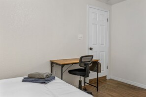 Eine kleine, einfache Unterkunft mit einem Bett, einem Schreibtisch und einem Stuhl.