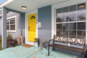 Eine Veranda mit einer Bank, einer gelben Tür und einem Briefkasten.