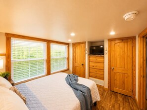 Une chambre avec deux lits, une armoire en bois et un téléviseur.