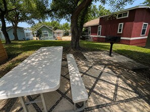 A picnic table with a bench in a park area with houses in the background. - Lake Travis Cabin Family Fun Resort Pool & Hot Tub (Austin)
